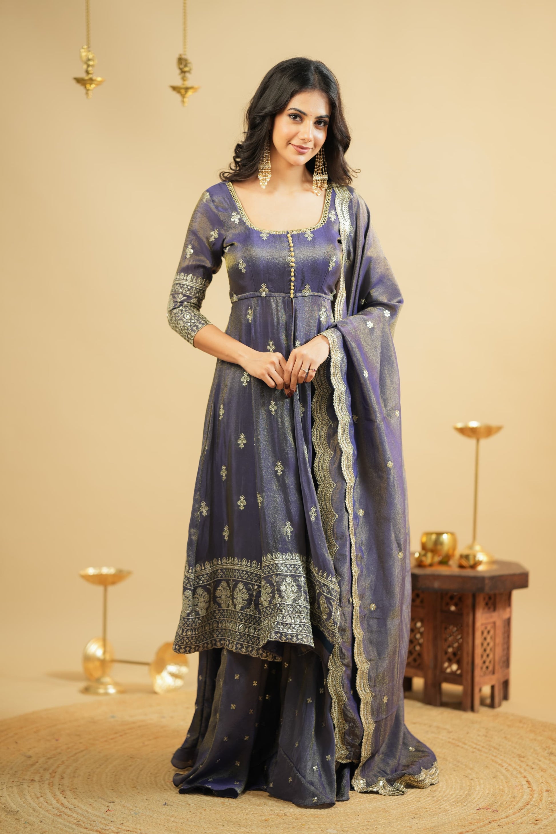 Woman in a traditional blue and silver outfit with a beige background