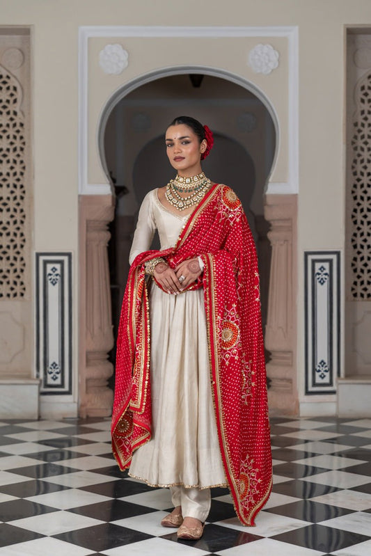 Woman in traditional red and white outfit standing in a decorative interior setting
