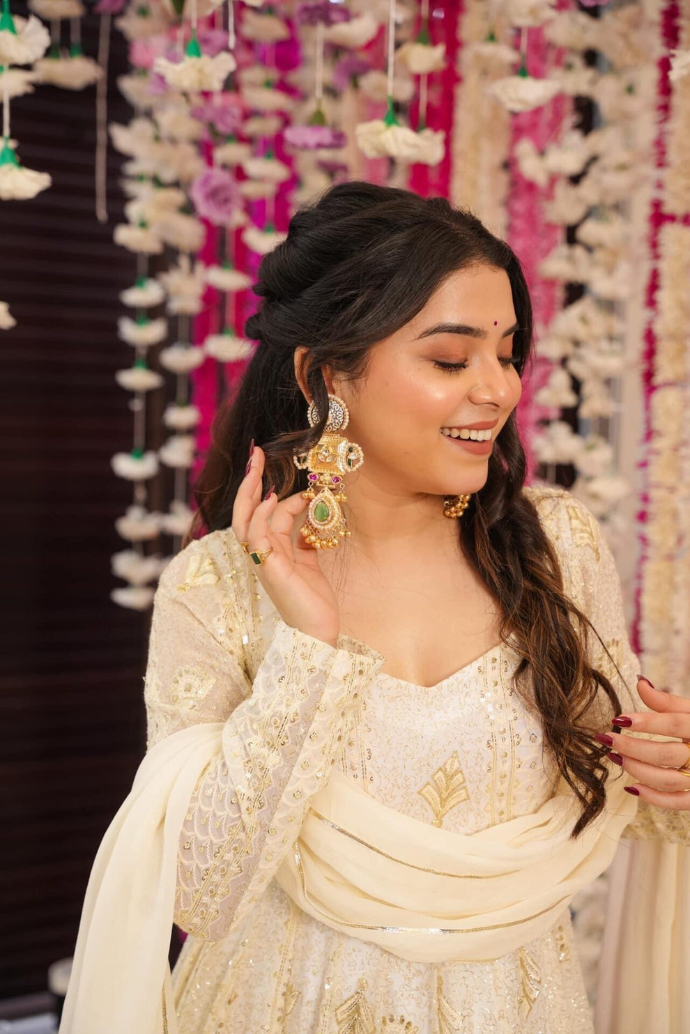 Woman in traditional attire with jewelry against a decorative background