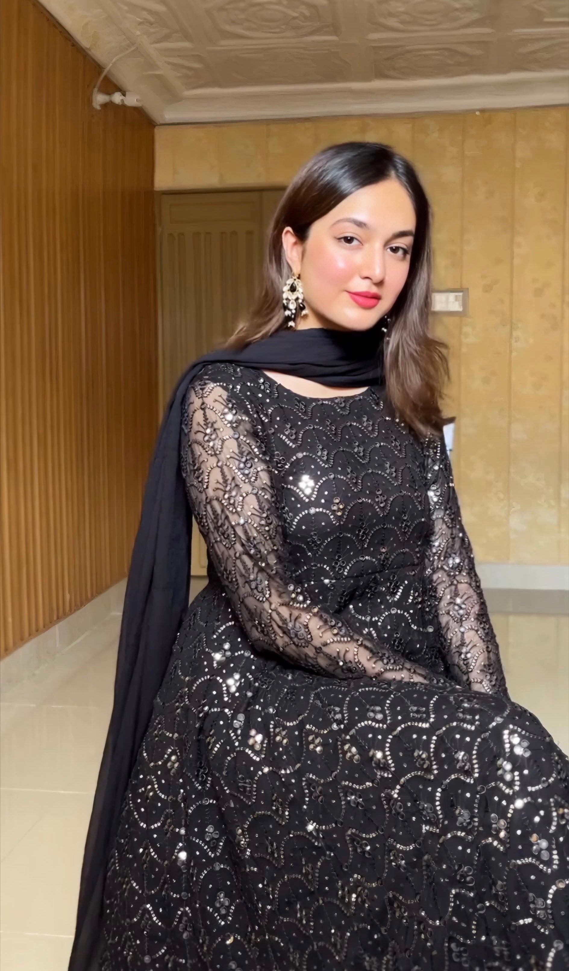 Woman wearing a black lace dress with a hood in an indoor setting