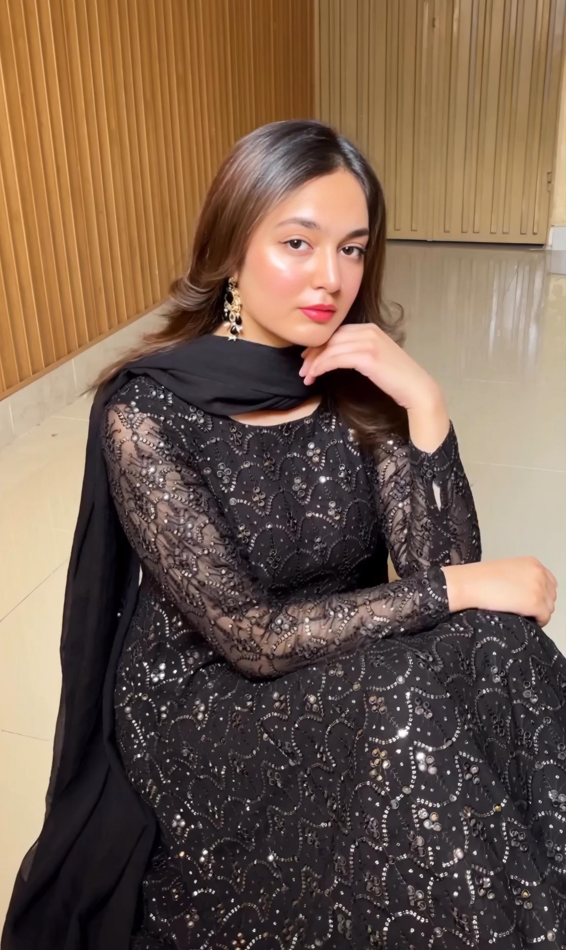 Woman wearing a black lace dress with a plain background