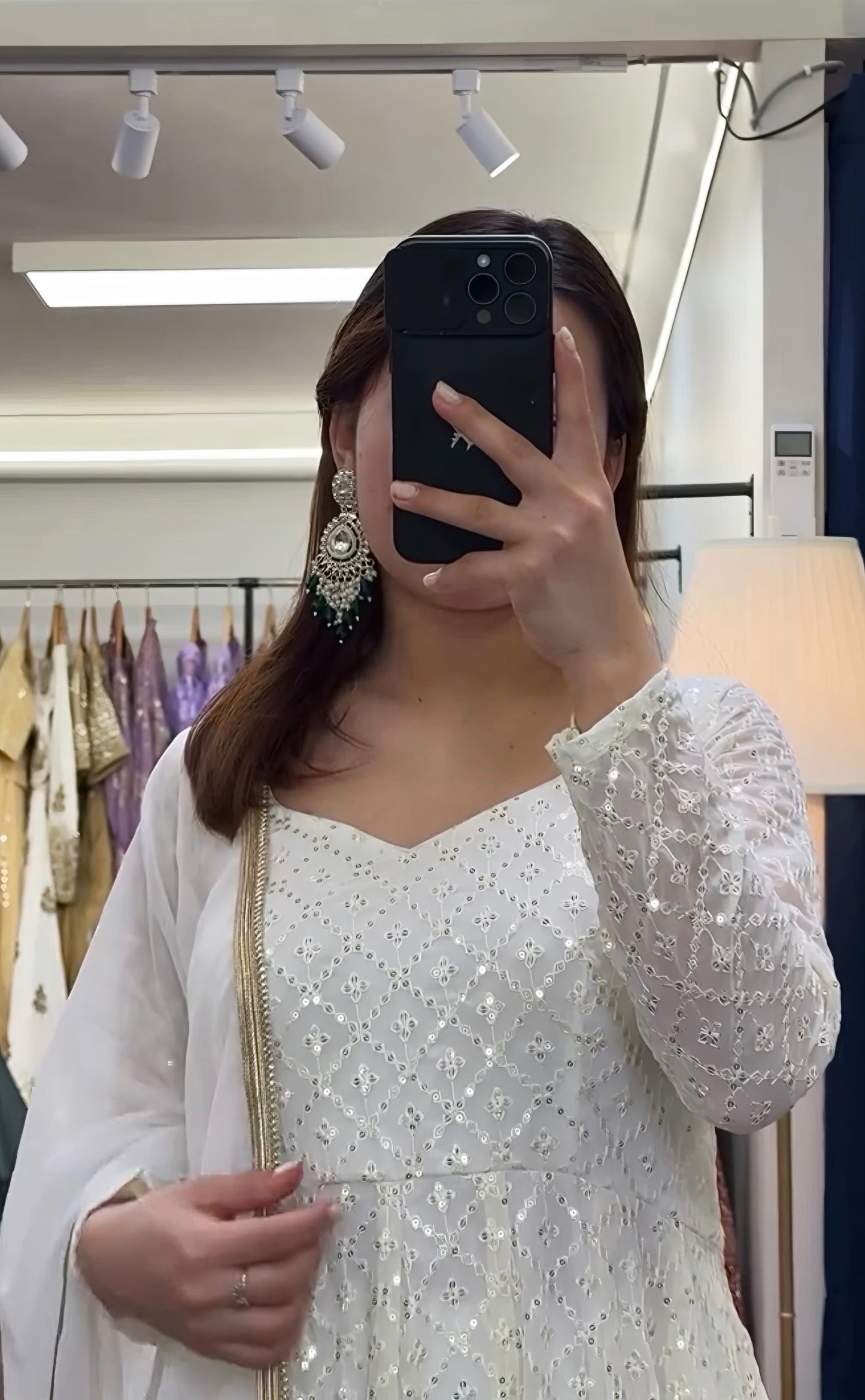 Person wearing a white embroidered outfit in a store setting