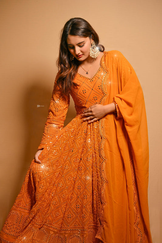 Woman wearing an orange embroidered traditional outfit with a beige background