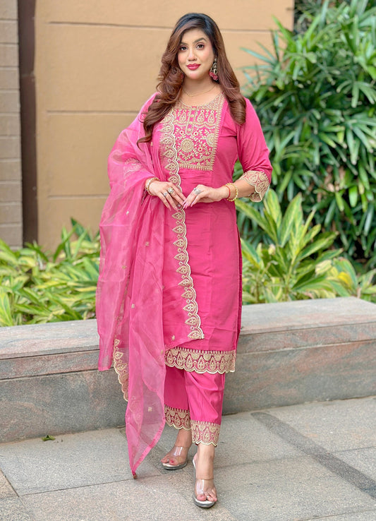 Woman in a pink traditional outfit with embroidery, standing outdoors.