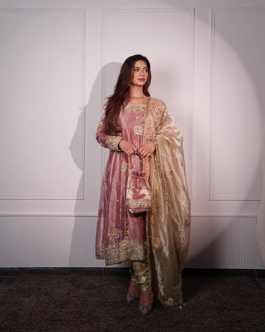 Woman in traditional pink and gold outfit against a white wall