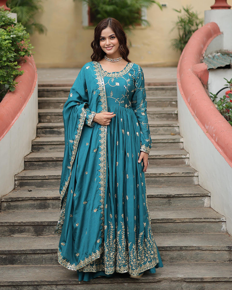 Woman in a teal embroidered dress standing on steps outdoors
