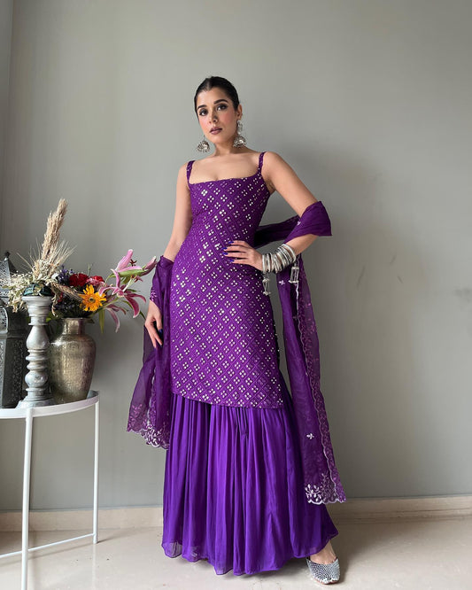Woman in a purple traditional outfit standing indoors with a neutral background