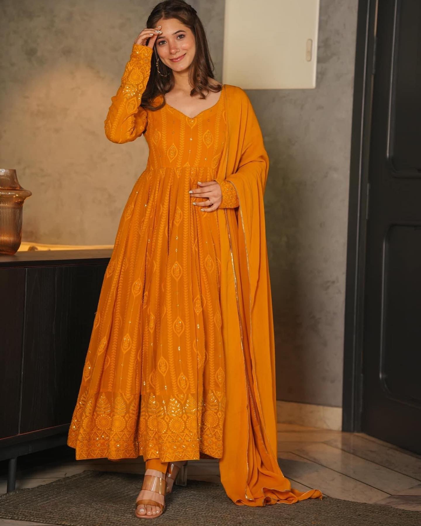 Woman wearing a mustard yellow dress with a matching dupatta indoors.