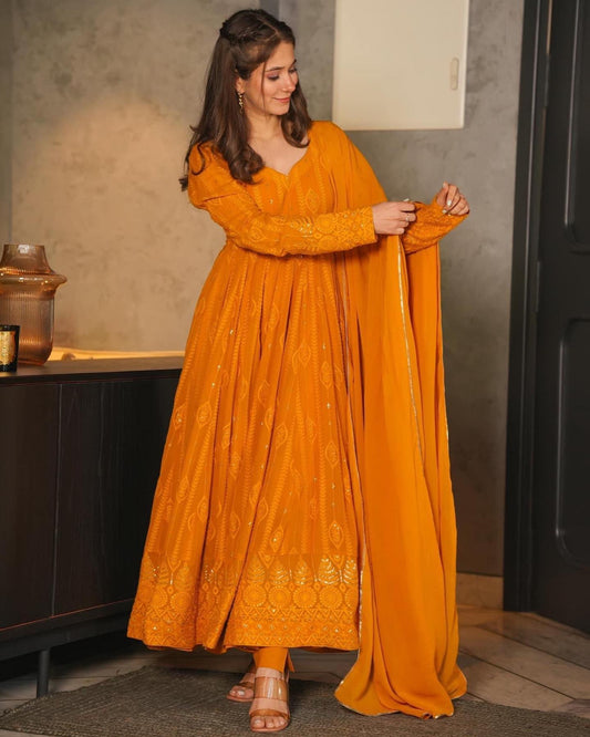 Woman wearing a mustard yellow embroidered dress indoors.